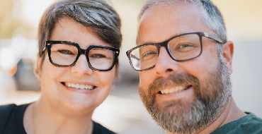 A smiling couple wearing glasses outdoors photo